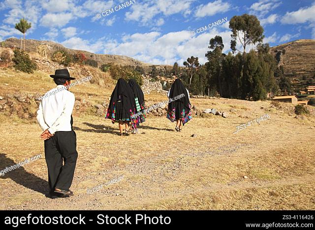 Local people wearing traditional dress walking on the hill in Amantani island, Lake Titicaca, Puno Region, Peru, South America