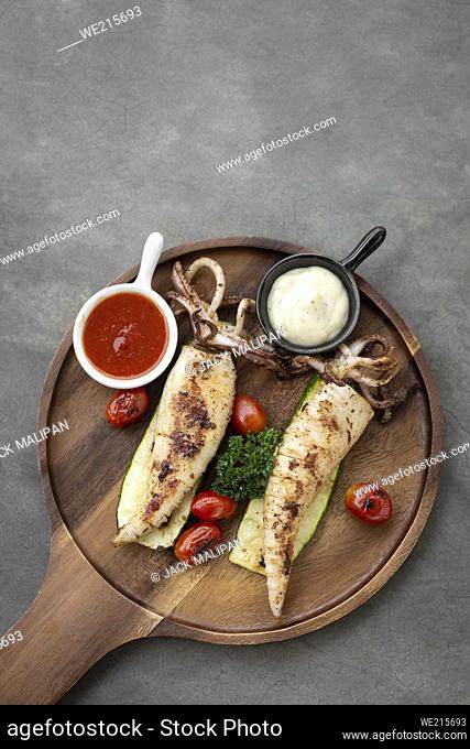 grilled whole squid with aioli and spicy sauce in spanish tapas restaurant