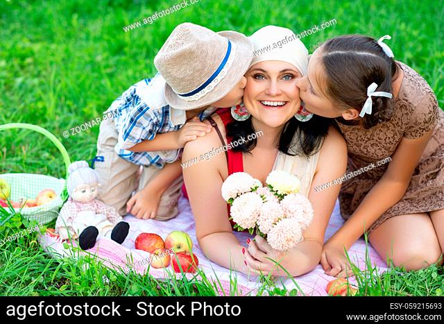 beautiful mother with son and daughter having picnic on grass. oudoor shot