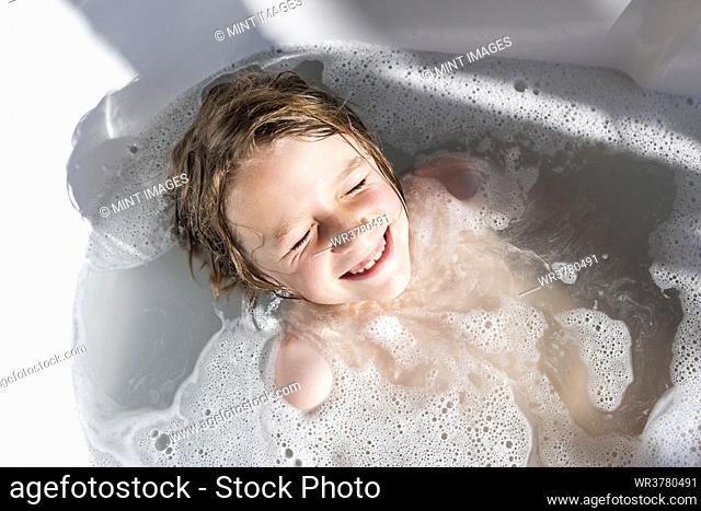 Eight year old boy in a bathtub, having a bath