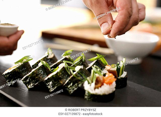 Klasyczne grube rolki futomaki podane na kamiennym talerzu. Kuchnie swiata, japonskie sushi. Sushi master przygotowuje sushi w japonskiej restauracji