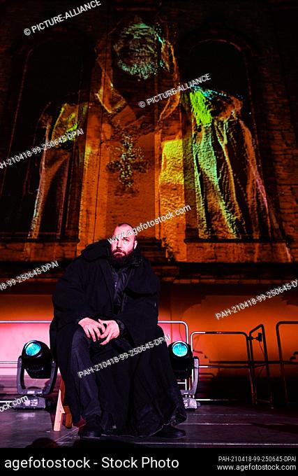 14 April 2021, Rhineland-Palatinate, Worms: Actor Isaak Dentler sits on stage in front of a light projection at the Dreifaltigkeitskirche during a media...