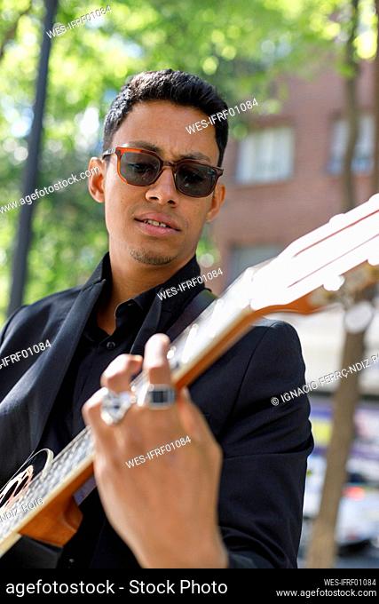 Male musician wearing eyeglasses playing guitar