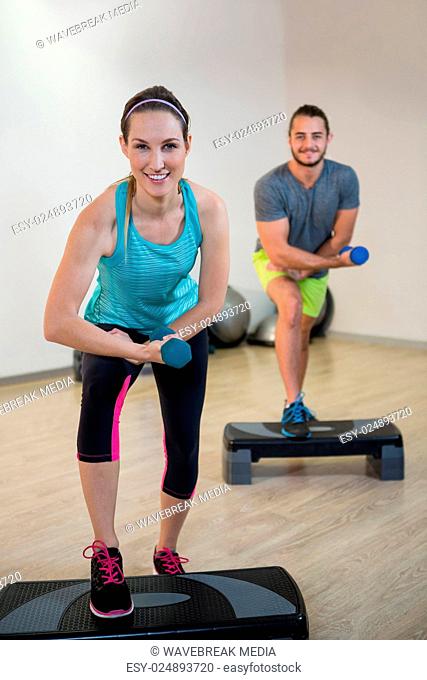 Portrait of man and woman doing aerobic exercise with dumbbell
