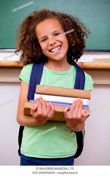 Portrait of a smiling schoolgirl holding her books