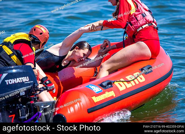 15 July 2021, Mecklenburg-Western Pomerania, Prerow: Lifeguards Pauline Geipel (front) and Jasmin Luciani from the DLRG water rescue pull a woman out of the...
