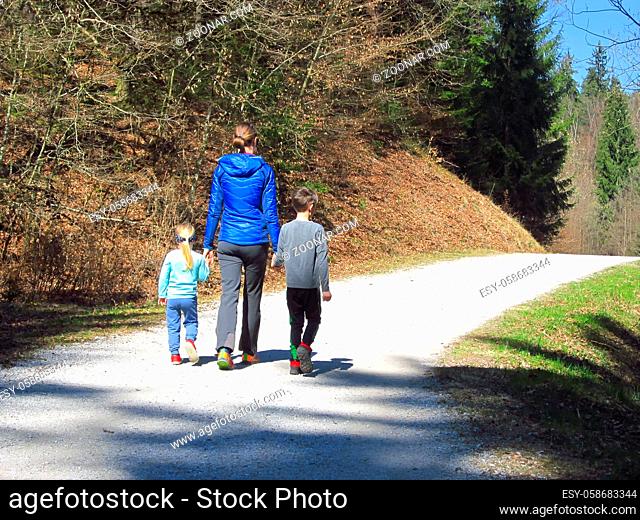 Mother with son and daughter hiking and having fun and beeing happy together and holding hands. Family trip in a forest at spring