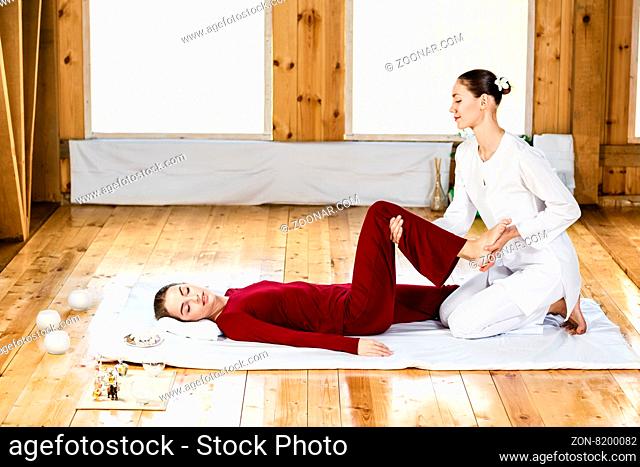 Young woman getting traditional thai stretching massage by therapist