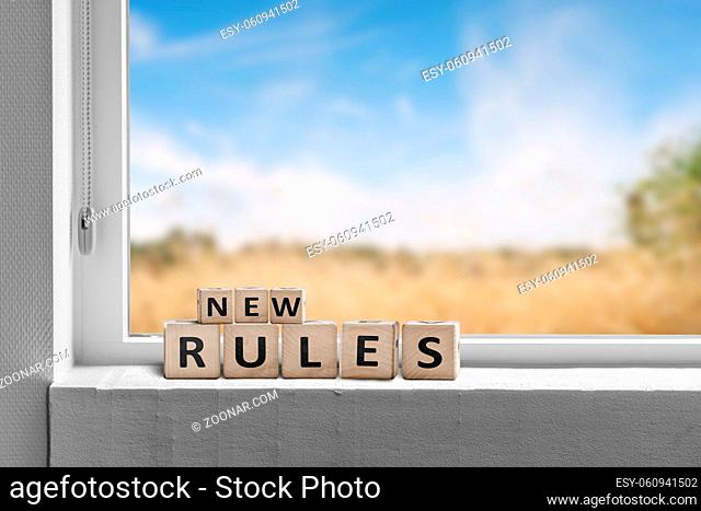 New rules sign in a window with a view to fields under a blue sky