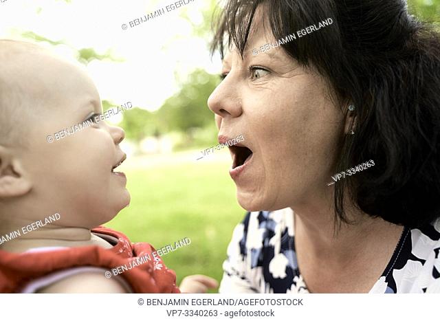 middle-aged grandmother with granddaughter baby toddler outdoors in park