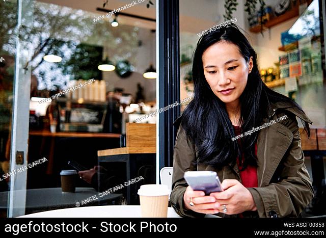 Woman using mobile phone at cafe