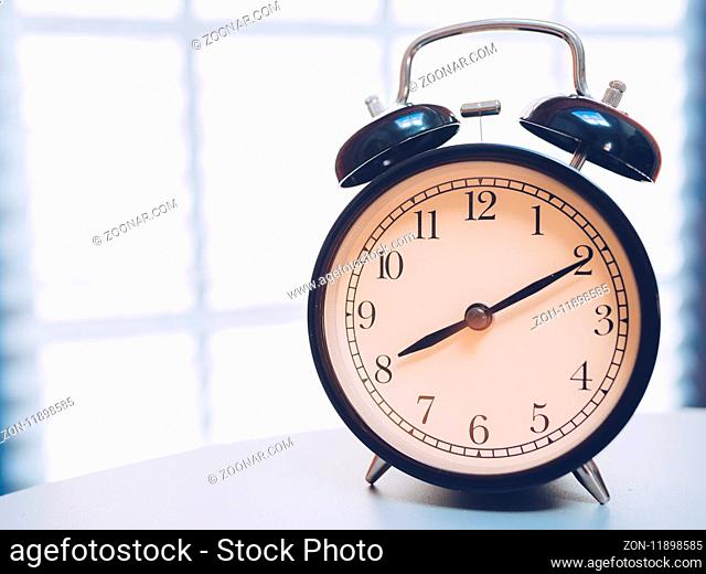 Retro alarm clock on table with vintage background