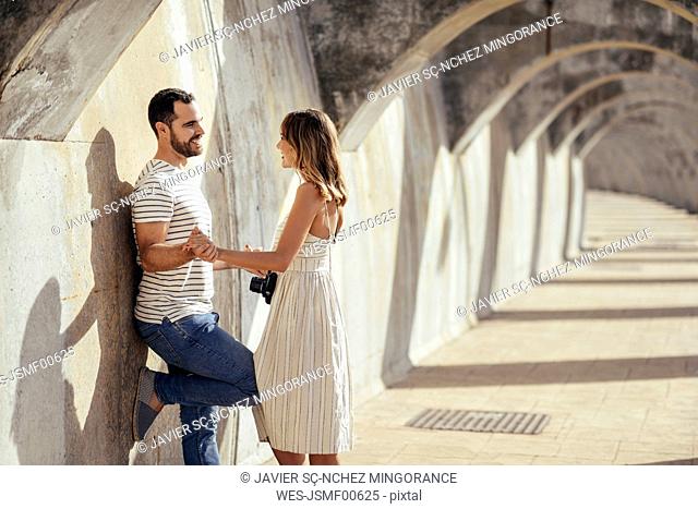 Spain, Andalusia, Malaga, happy affectionate tourist couple under an archway in the city