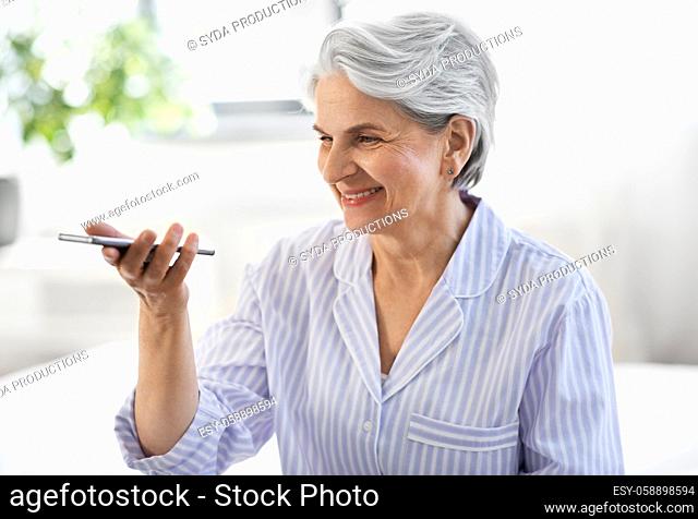 happy senior woman recording voice on smartphone