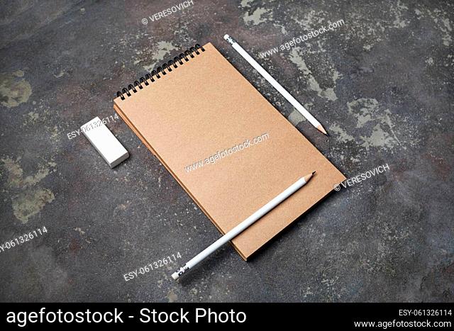 Blank kraft notebook, pencils and eraser on concrete background. Responsive design template