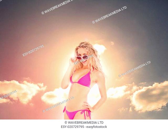Blonde woman with sunglasses posing under the sun in bikini