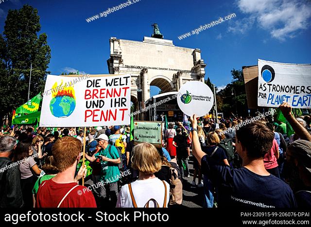 15 September 2023, Bavaria, Munich: Participants of a demonstration of the climate protection movement Fridays for Future hold up signs with the inscriptions...