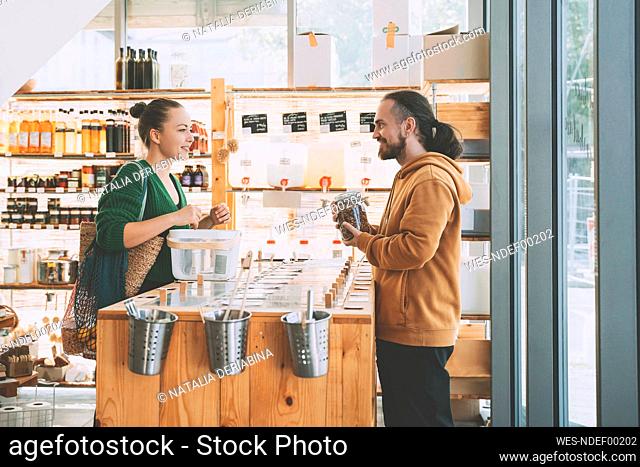 Man with mason jar talking to woman in zero waste shop