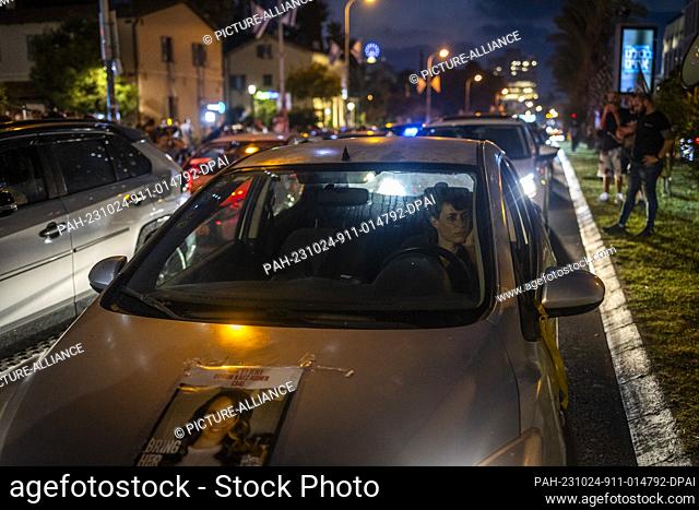 24 October 2023, Israel, Tel Aviv: An Israeli woman drives while sticking a poster on her car during a protest calling for immediate release of kidnapped by...