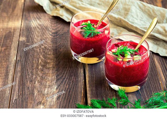 Beetroot gazpacho soup with cucumber and dill in glasses on rustic wooden background