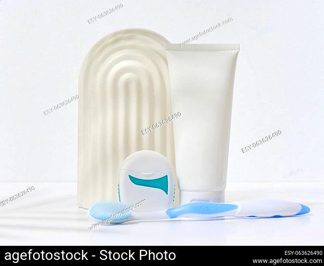 White plastic tube for toothpaste, toothbrush and dental floss on white background