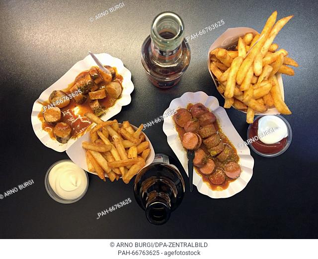 Two portions of fries, a portion of currywurst (l). two servings of mayonaise, ketchup, a beef currywurst, with bottles of Bionade and Alsterwasser