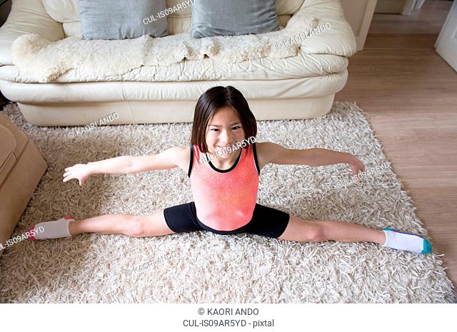 Girl practicing gymnastic splits on living room rug