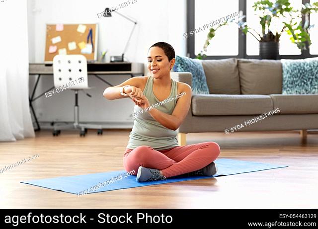 woman with smart watch and exercise mat at home