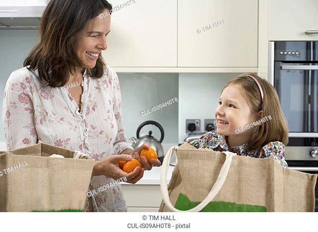 Mother and young daughter unpacking shopping bags