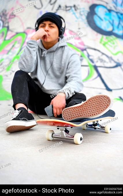 Young latin skater man posing with skateboard at skate park