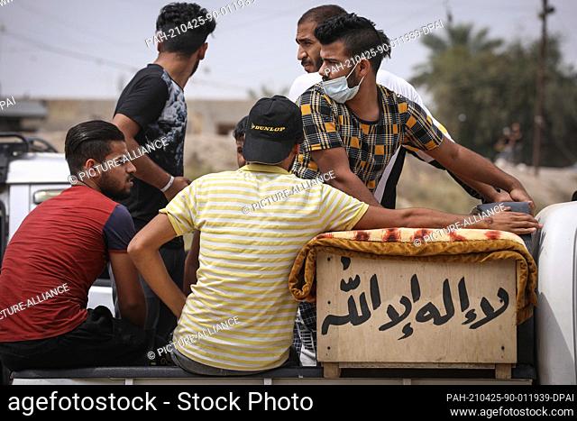 24 April 2021, Iraq, Baghdad: Mourners ride on a truck with the coffin of Ali Khodeir Ibrahim, one of the COVID-19 patients who were killed in the blaze at Ibn...