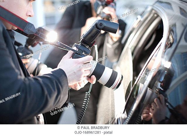 Paparazzi holding camera lens to car window