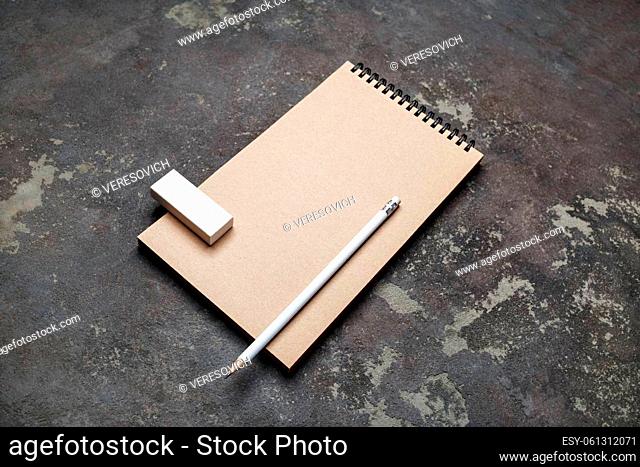 Blank kraft notepad, pencil and eraser on concrete background. Responsive design mockup