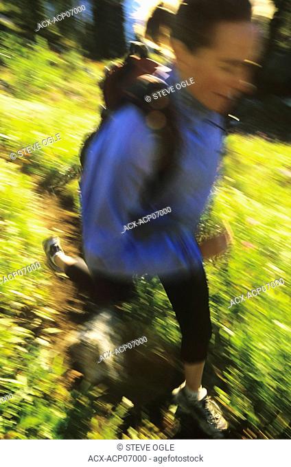 A woman trail-runner on a morning run through a wildflower meadow in Kokanee Provincial Park, British Columbia, Canada