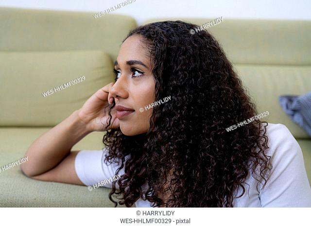 Young woman sitting at home, thinking