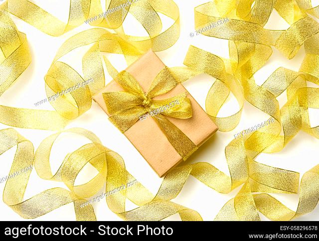 gift wrapped in brown paper on a twisted golden ribbon background, festive background, top view