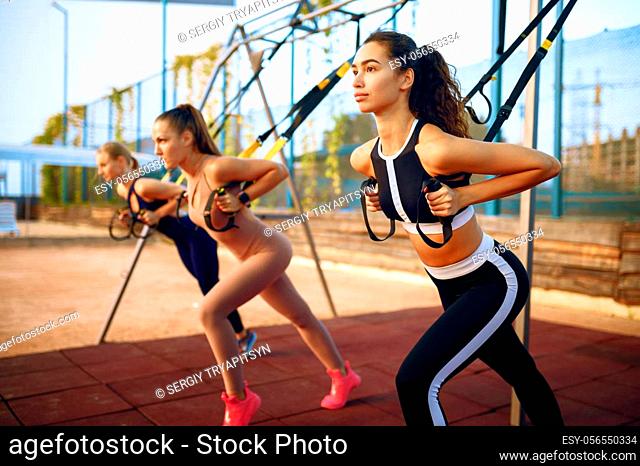 Slim women doing fit exercise with ropes on sports ground, outdoors group training. Female athletes in sportswear, team fitness workout, teamwork