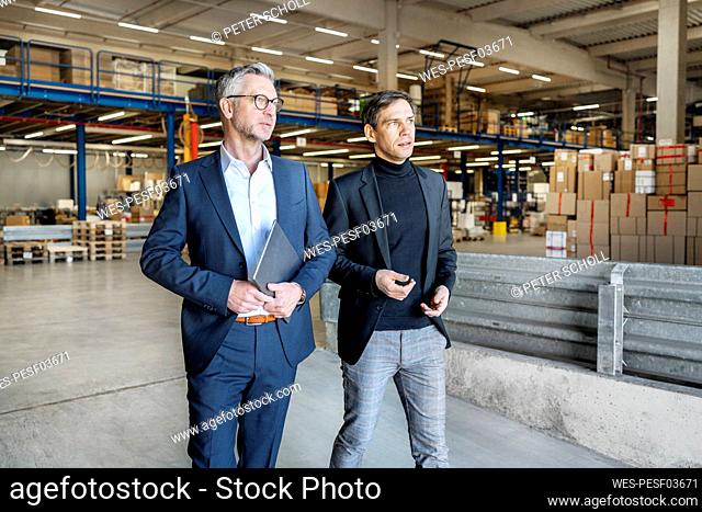 Mature businessman discussing with colleague at factory