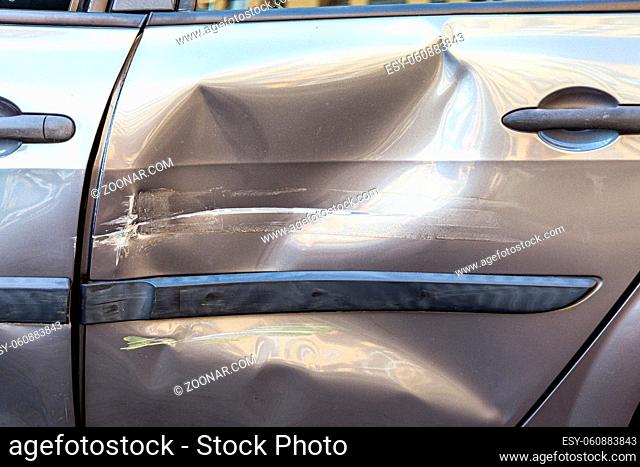 Closeup of damaged back door of car after accident on a road, dents and scratches on automobile body, side part of auto destroyed after crash