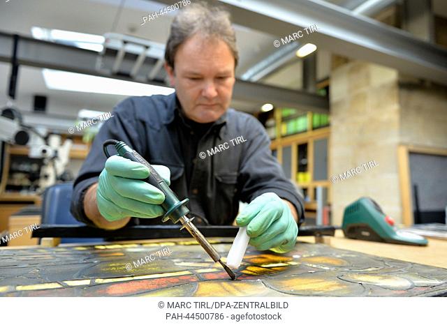Thomas Glass, glazier and restorer in the glass workshop of the Erfurt Cathedral, works at a built out window pane of the Cathedral in Erfurt, Germany