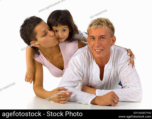 Happy family lying on the floor. Mother kissing daughter. Father looking at camera. White backgroung, front view