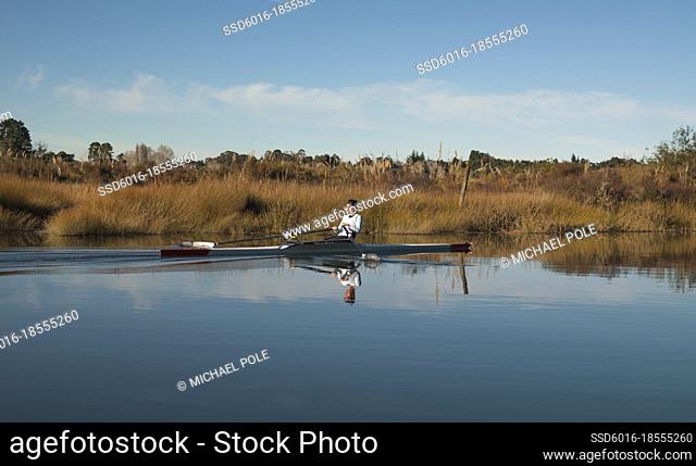 Young woman laying back in her single scull kayak on the water