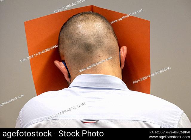 14 June 2023, Bavaria, Munich: The defendant covers his face with a file cover in the courtroom. The man allegedly had sex with a sleeping woman whom he was...