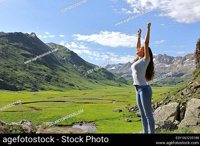 Excited casual woman raising arms in the mountain