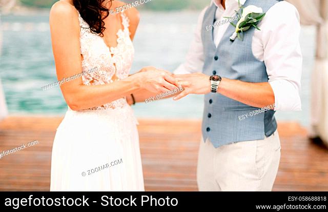 The bride puts the wedding ring on the groom's finger during the wedding ceremony by the sea . High quality photo