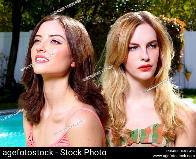 Closeup portrait of two women in vintage style bathing suits, istting outside by a pool