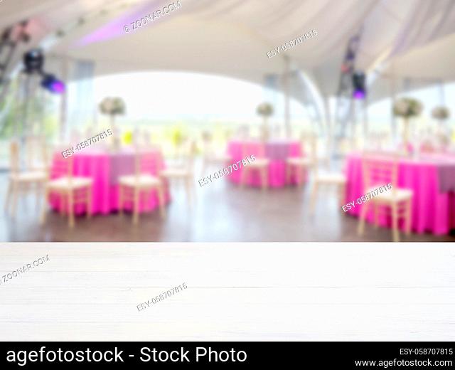 White wooden empty table in front of blurred restaurant interior background. Perspective white wood board over blur in restaurant or cafe - mockup for display...