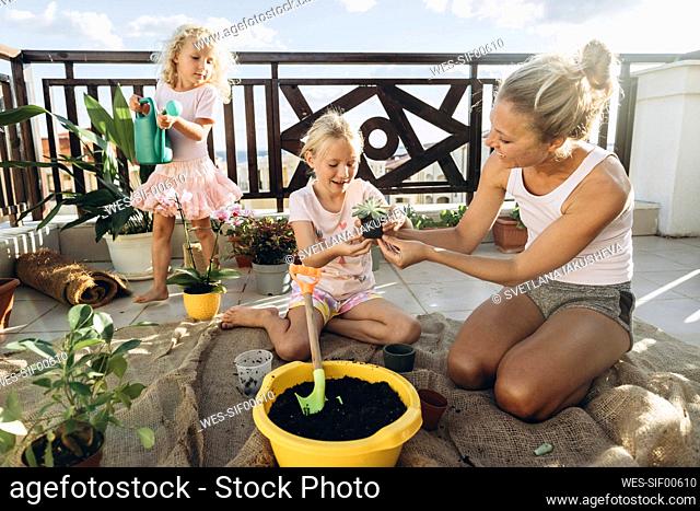 Mother and daughters planting on roof terrace together