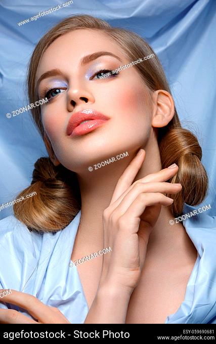 Beautiful young woman with blue makeup and hair nods. Beauty shot. Over blue textile background. Close-up