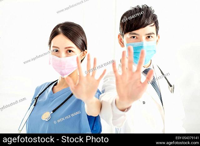 doctor in face mask and showing stop sign with hands